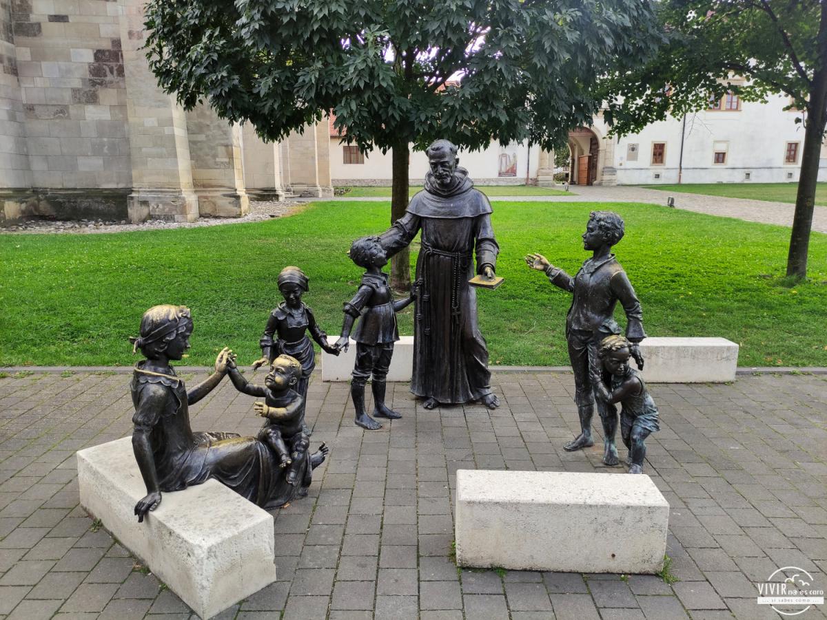 Escultura de bronce de un cura con un grupo de niños (Alba Carolina, Rumanía)